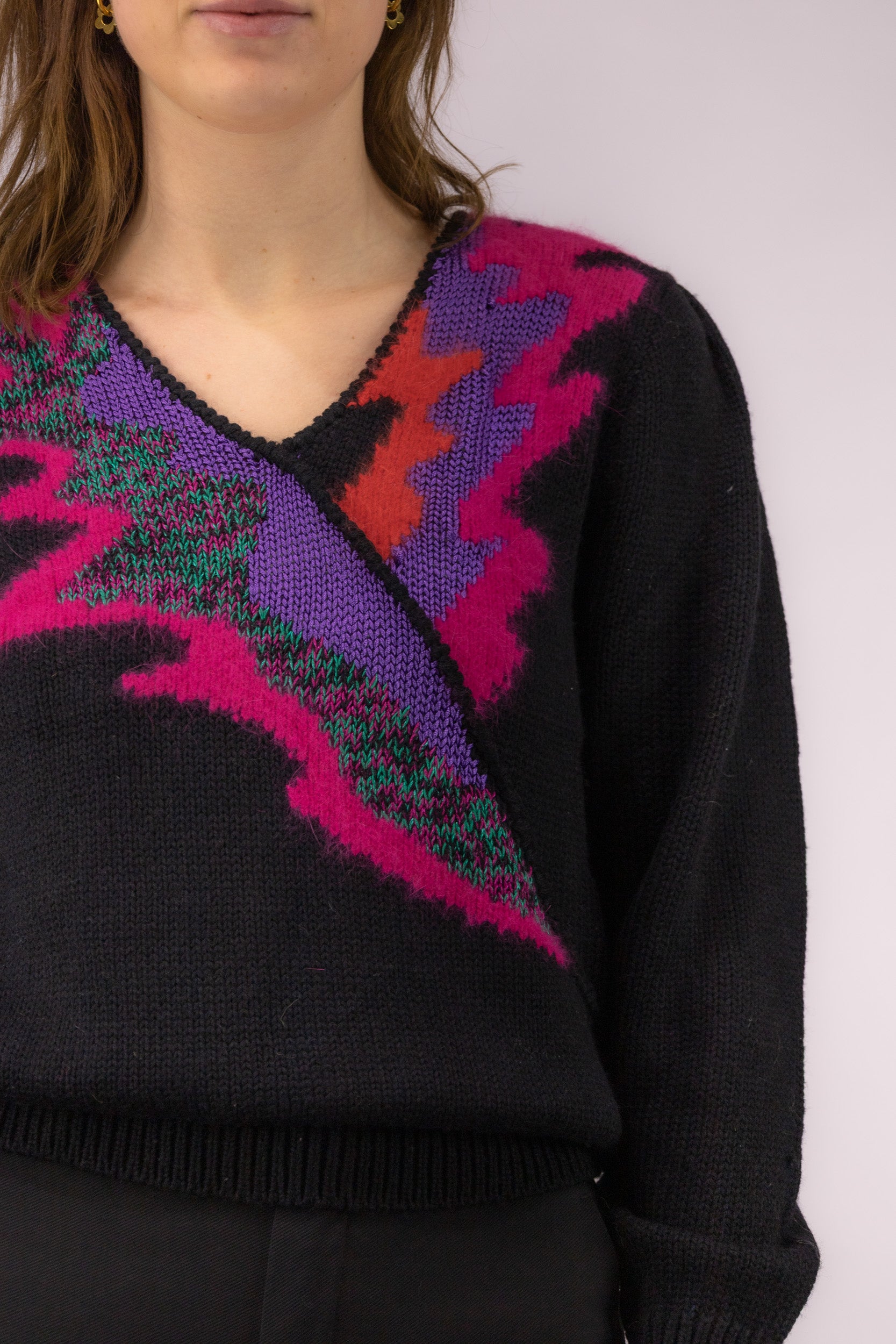 Detail van gekleurde halsafwerking op zwarte vintage trui met overslageffect