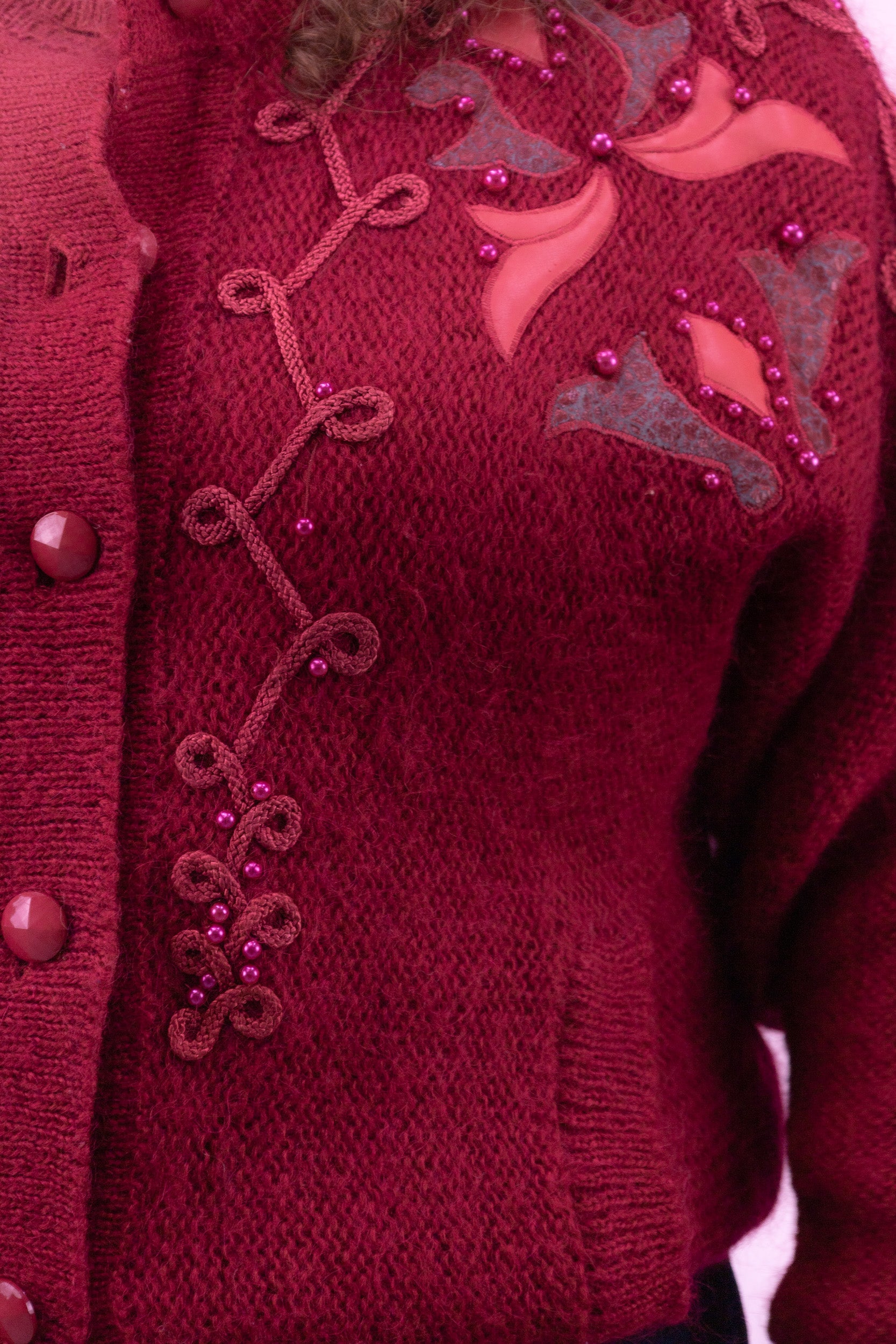 Detail van geborduurde patch met kralen op donkerroze vintage vest