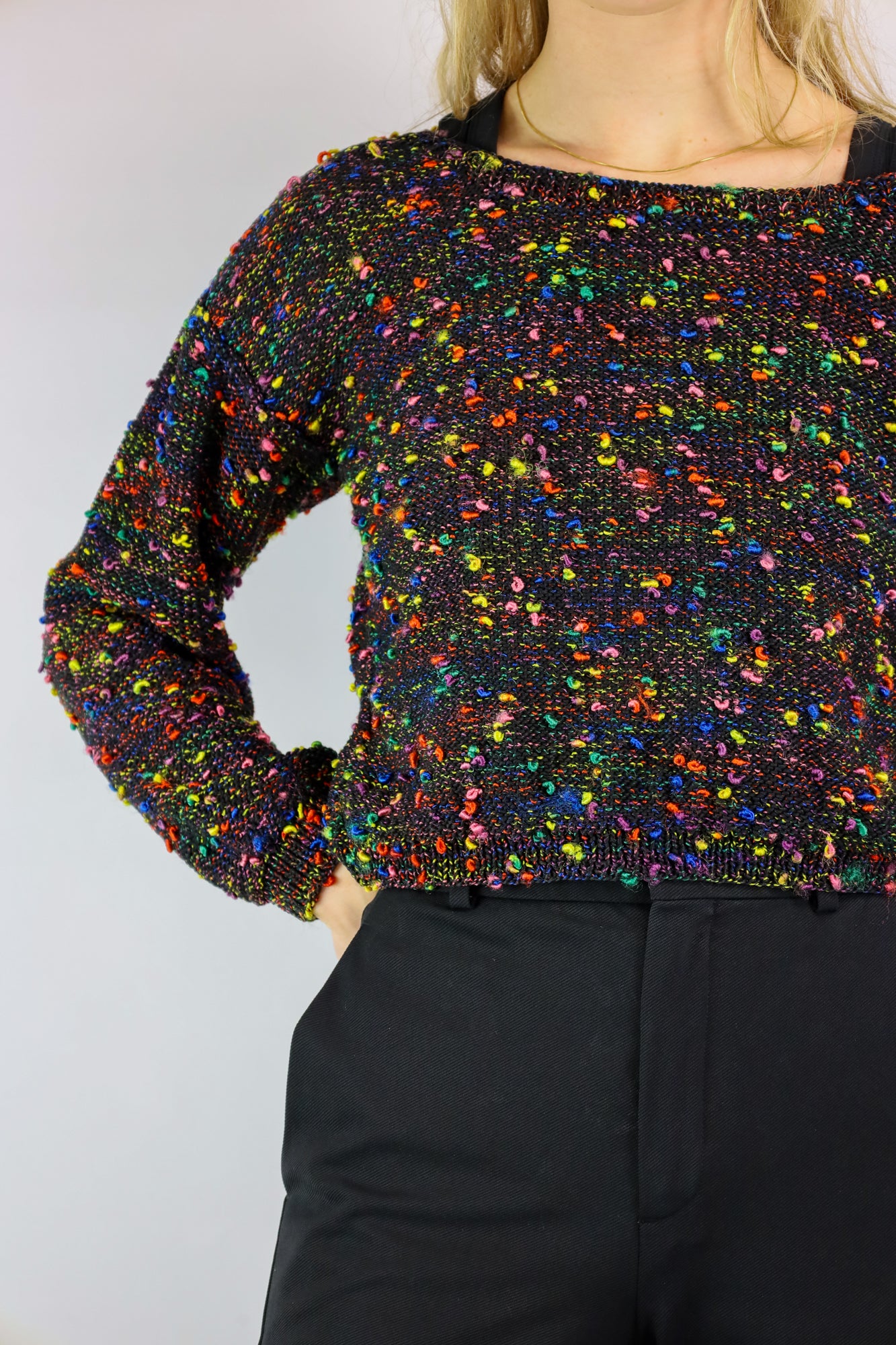 (EN) Close-up of a black vintage sweater with playful colorful pom-poms.
(NL) Close-up van een zwarte vintage trui met speelse kleurrijke bolletjes.