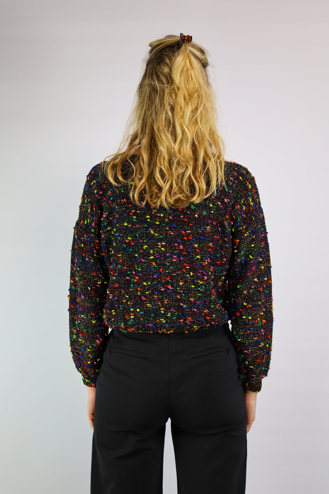 (EN) Full view of a cropped black sweater with colorful woven details.
(NL) Volledig beeld van een cropped zwarte trui met kleurrijke ingeweven details.
