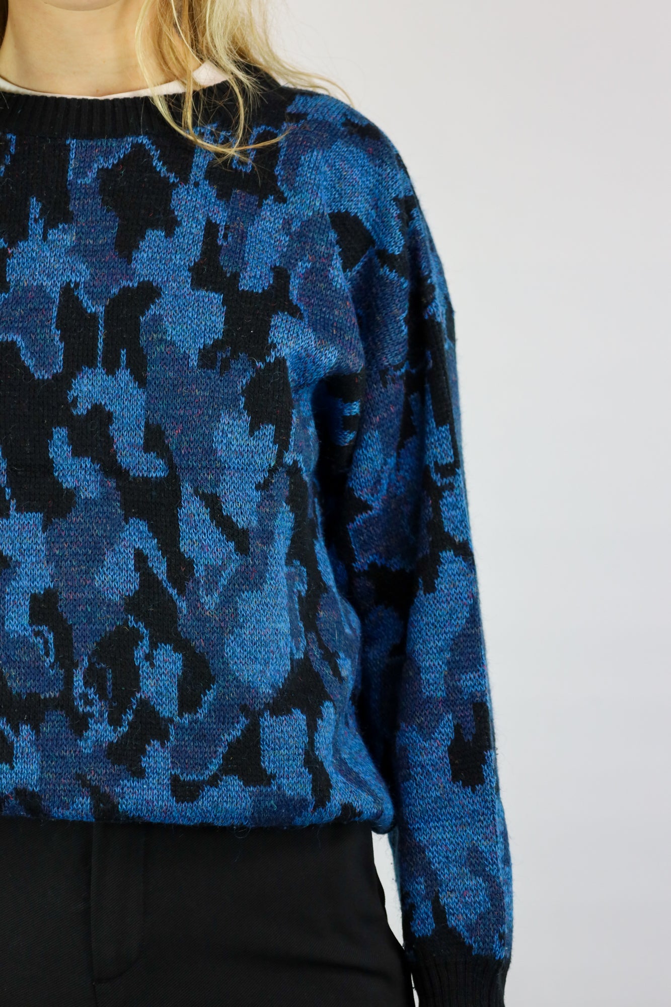 (EN) Close-up of a soft knit sweater with intricate blue organic patterns.
(NL) Close-up van een zachte gebreide trui met ingewikkelde blauwe organische patronen.