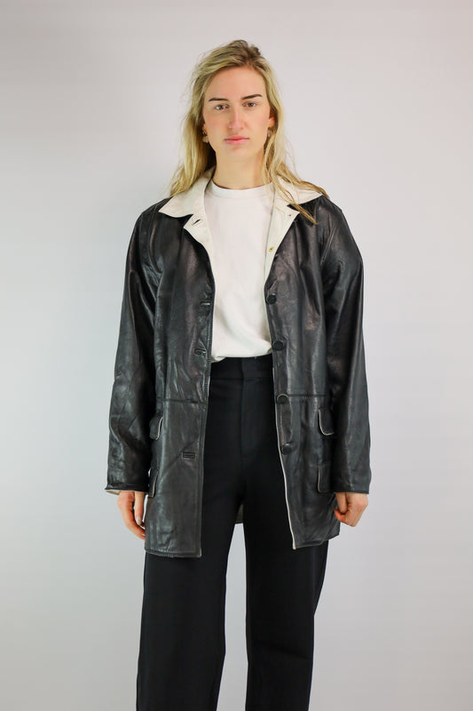 Vintage jas met zwart-wit leren details en losse ceintuur.
