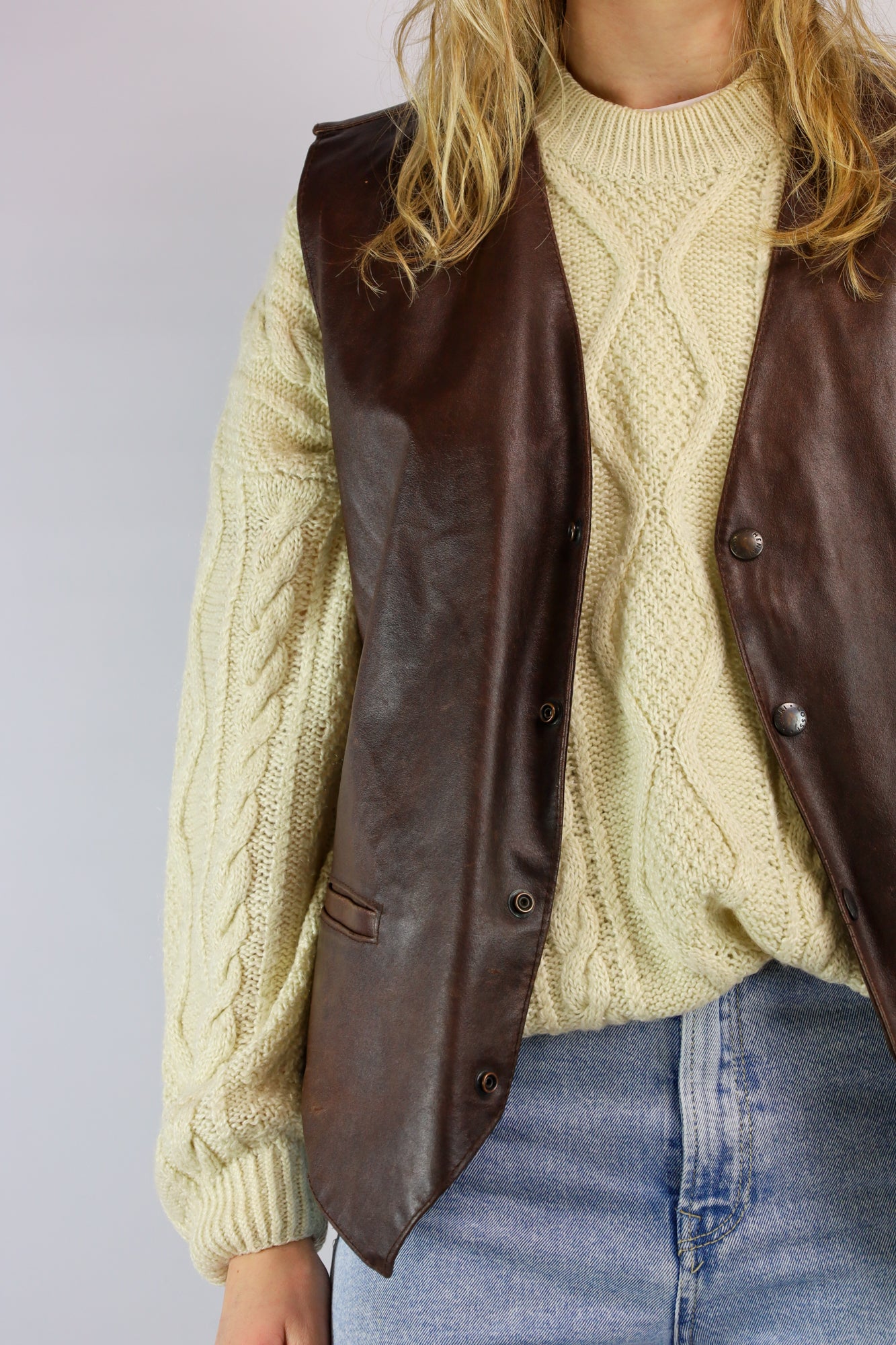 (EN) Close-up of a buttery soft brown leather vest with classic stitching.
(NL) Close-up van een boterzacht bruin leren gilet met klassieke stikdetails.
