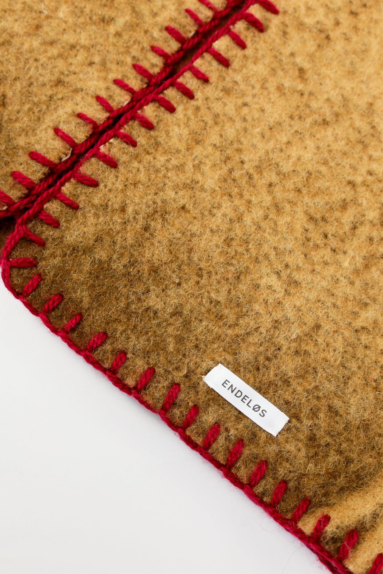 Close-up of the textured wool fabric with rich red stitching for contrast.