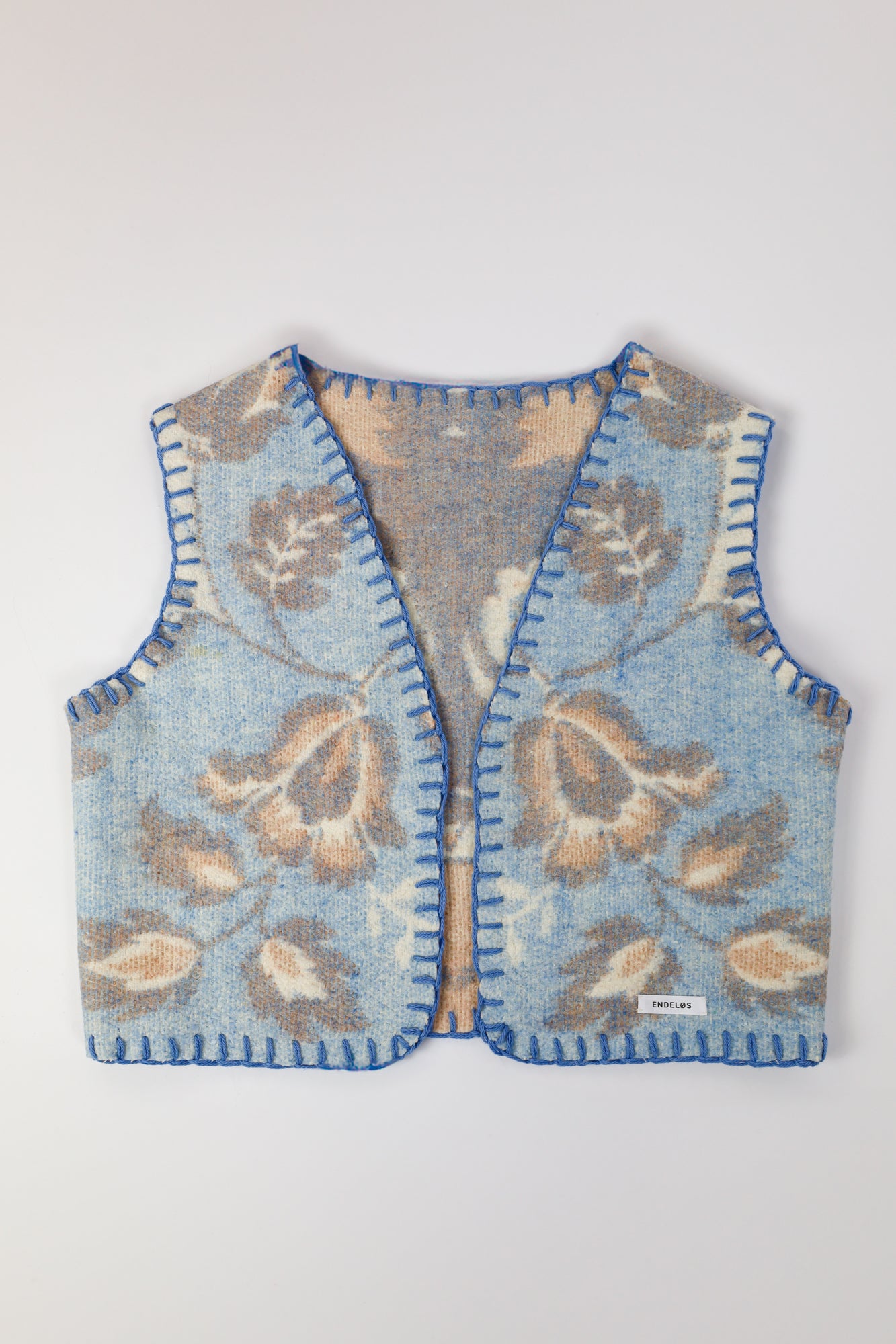 Front view of the handmade oversized vest, featuring soft pastel hues of blue and brown.