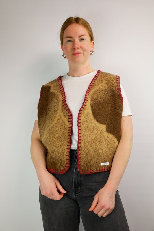 Vooraanzicht van een oversized gilet, gemaakt van een vintage wollen deken, afgewerkt met bordeauxrood garen.