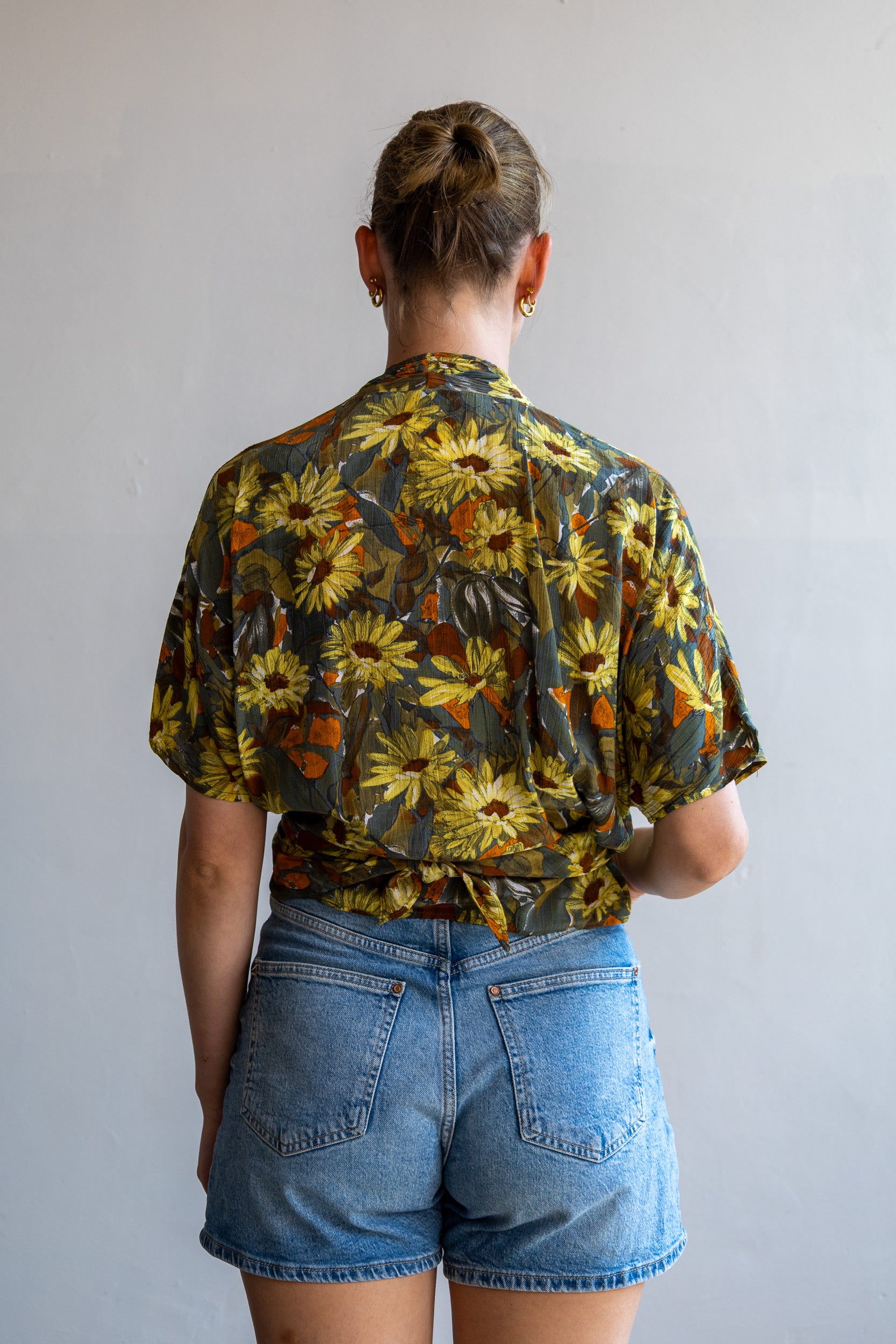 Achterzijde van de vintage zijden wikkelblouse met doorlopende bloemenprint.
