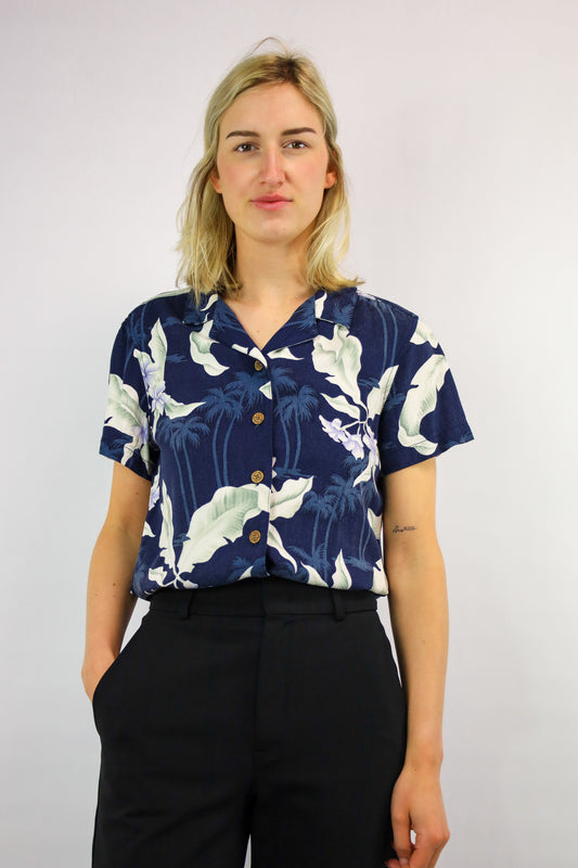 Korte vintage blouse met blauwe basis en tropische bloemenprint, gefotografeerd van voren.