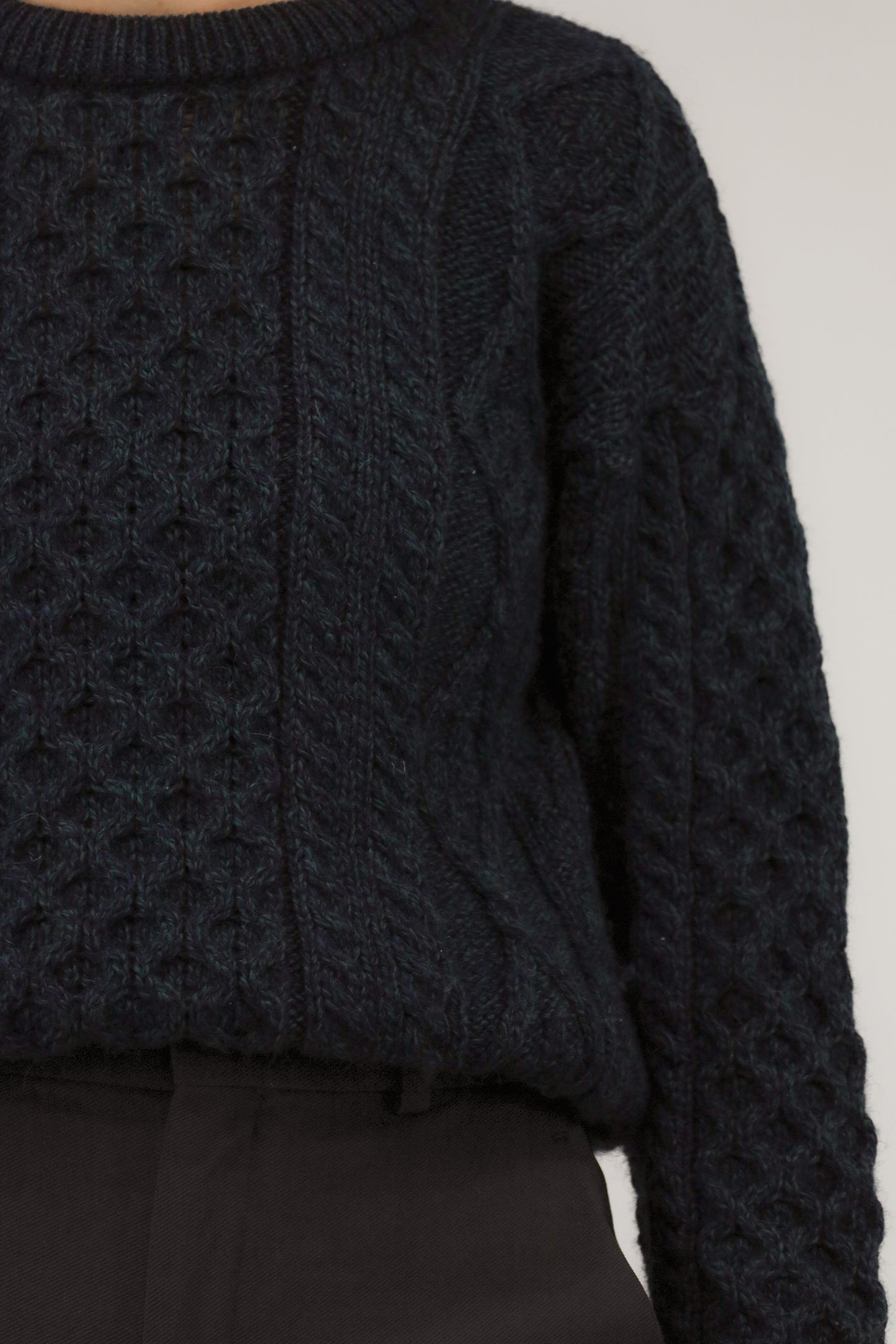 Detailopname van wolstructuur en ingebreid patroon in blauw en groen garen.