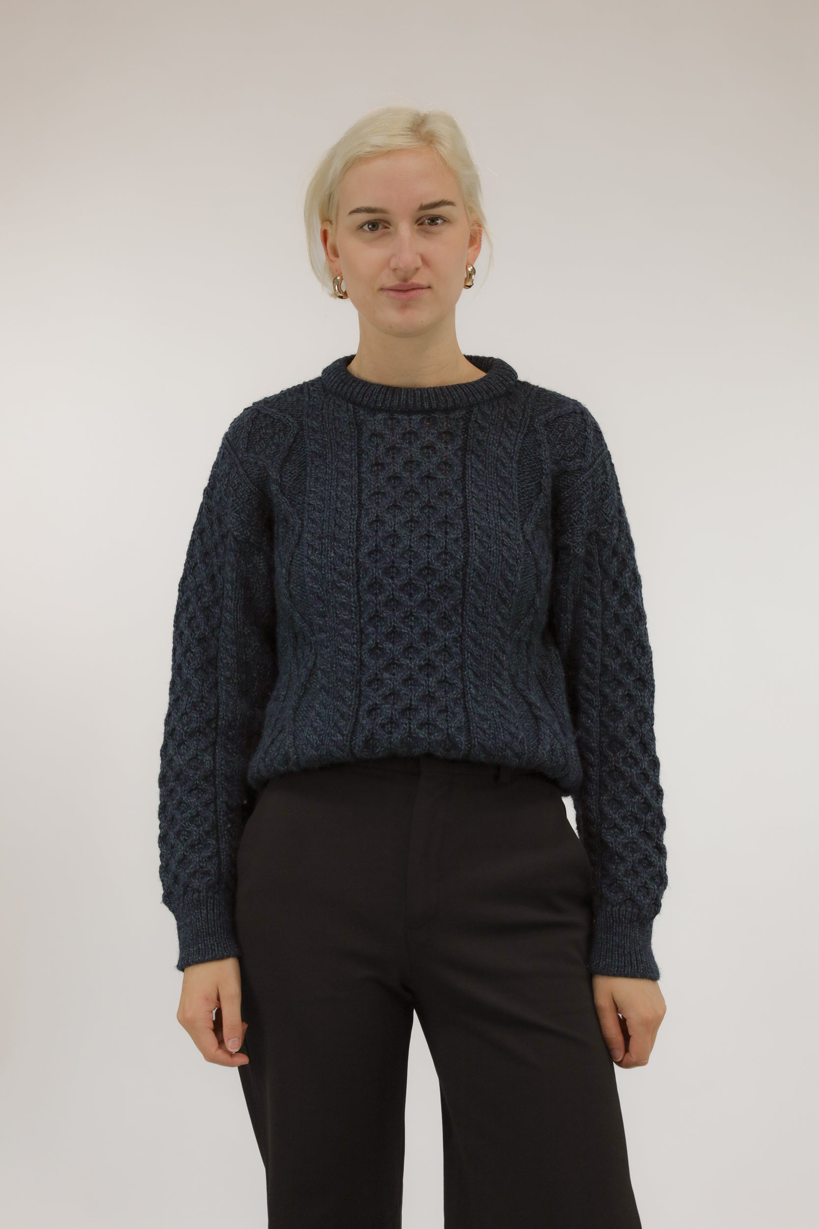 Vooraanzicht van model met blauwe en groene wollen trui met ingebreid dessin.