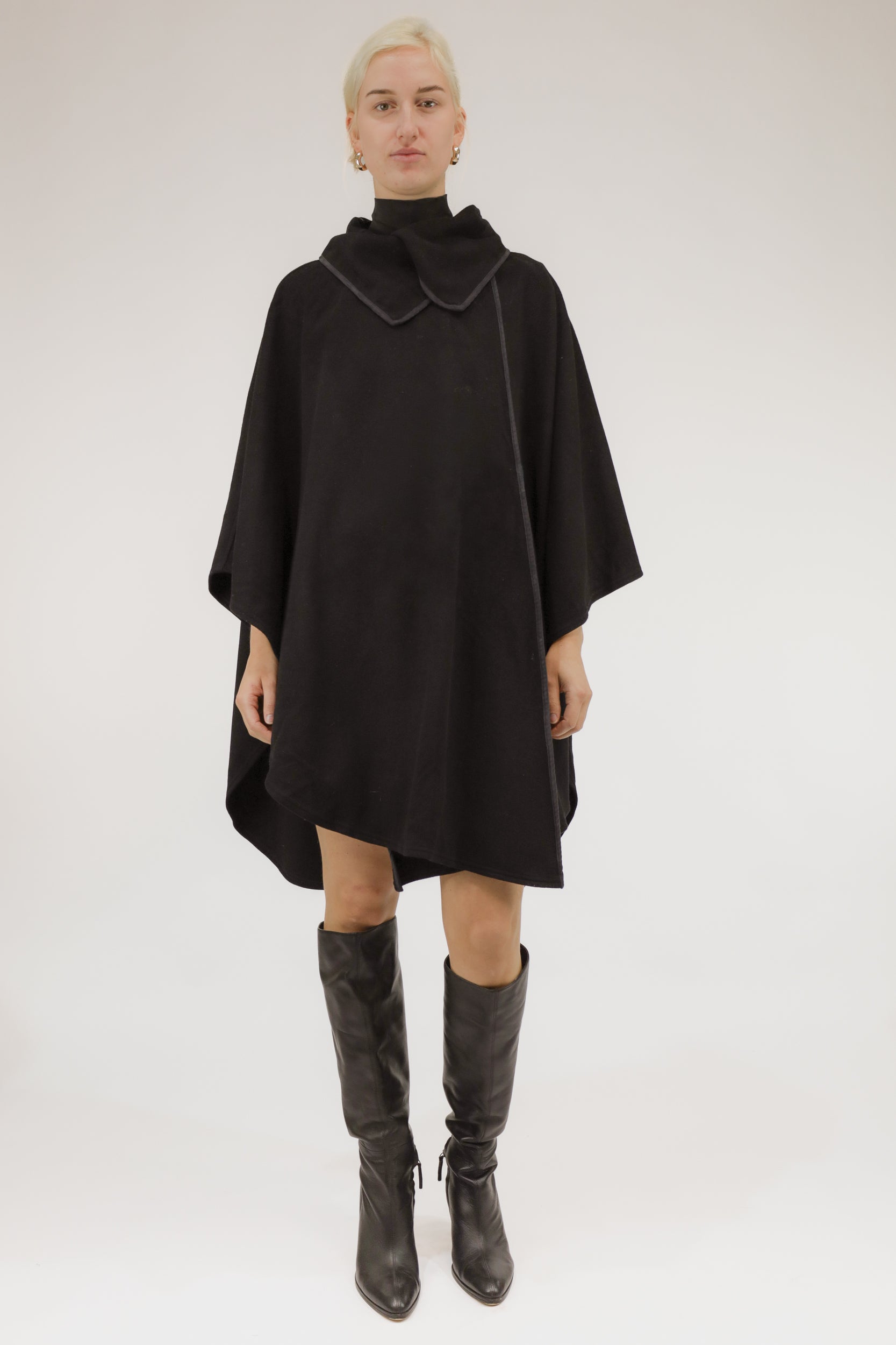 Vooraanzicht van model met zwarte wollen poncho met overslag.